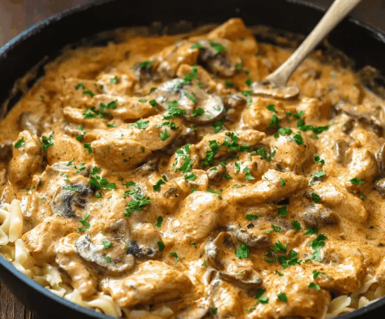 Creamy chicken stroganoff served over noodles with mushrooms and herbs, perfect for a hearty and flavorful meal.