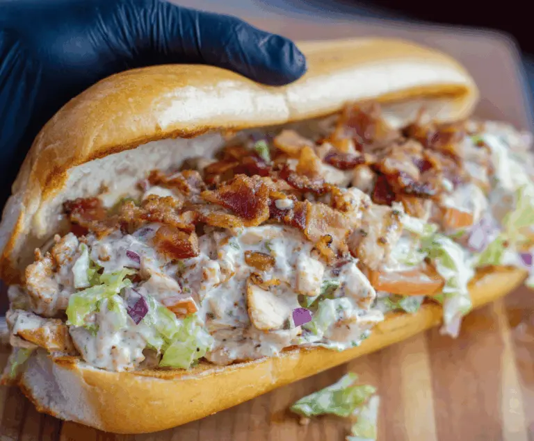 Delicious chopped chicken bacon ranch sandwich with fresh lettuce, tomato, and melted cheese on toasted bun, ready to enjoy.