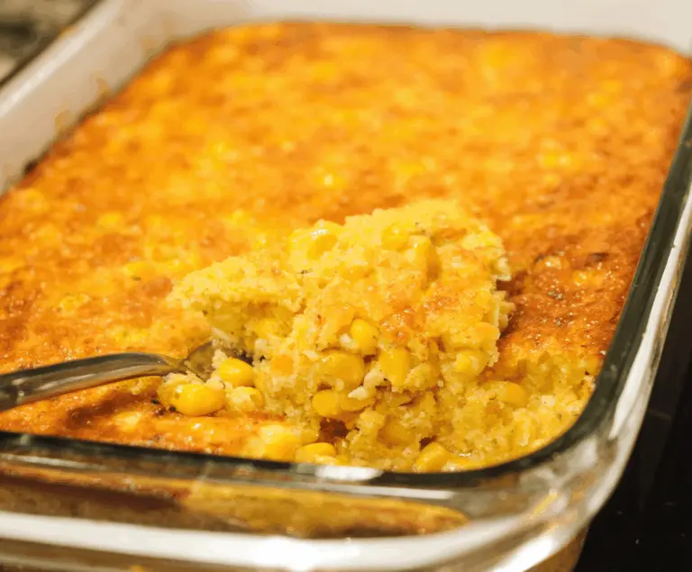 Creamy, golden corn pudding topped with melted butter and fresh herbs, served in a rustic ceramic dish, perfect for a comforting side dish