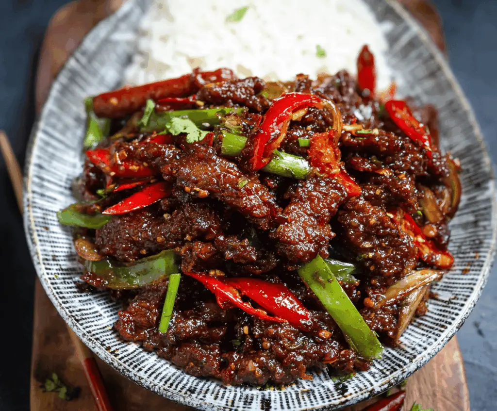 Delicious crispy chilli beef served on a plate with garnishes, showcasing a flavorful Asian-inspired spicy stir-fry dish