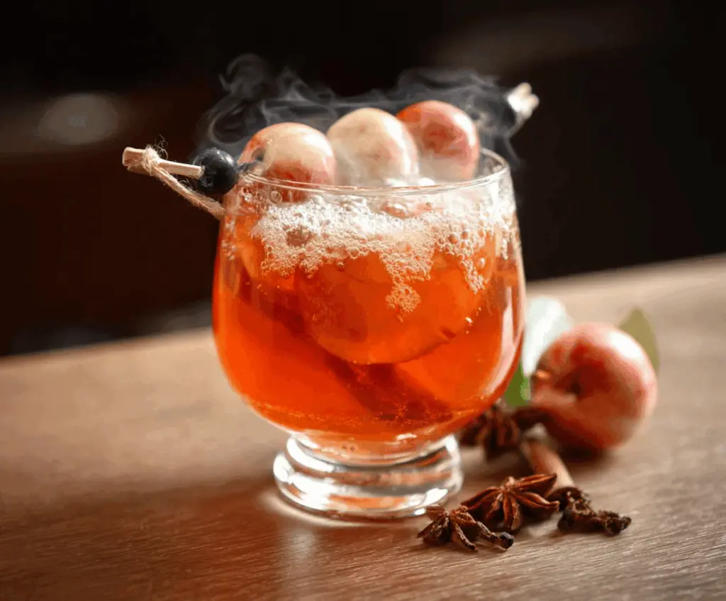 Spooky Poisoned Apple Cider in a glass with cinnamon sticks and apple slices, perfect for Halloween celebrations