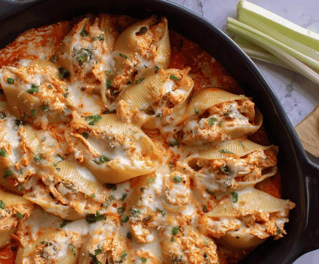 Delicious Buffalo Chicken Stuffed Shells garnished with fresh herbs on a white plate.