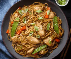 Delicious chicken teriyaki noodles garnished with green onions on a white plate.