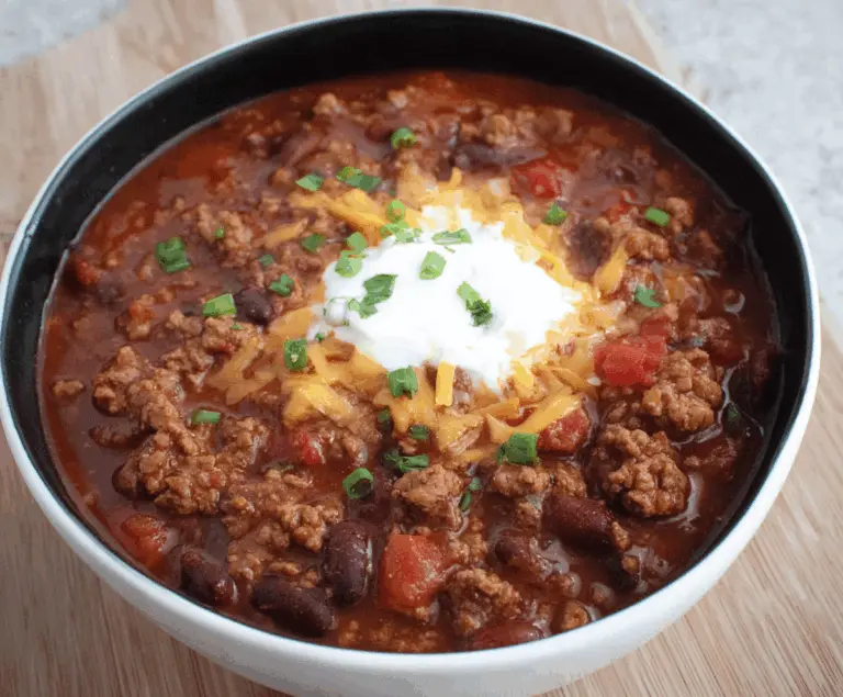 Delicious ground beef stovetop chili ready to serve with fresh herbs and melted cheese.