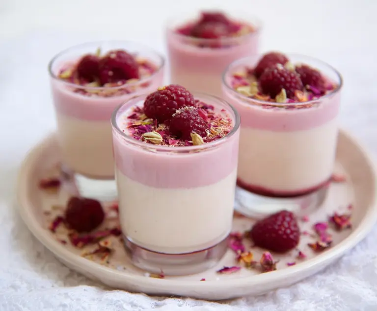 Delicious Raspberry Rose Panna Cotta Cups topped with fresh berries and edible flowers, perfect for a romantic dessert.