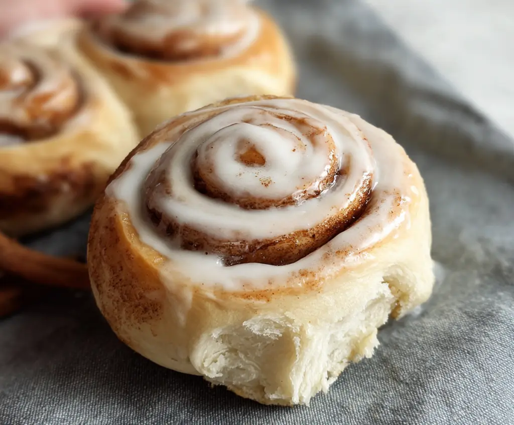 Delicious sourdough discard cinnamon rolls topped with icing on a baking tray.
