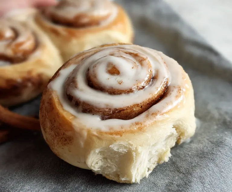 Delicious sourdough discard cinnamon rolls topped with icing on a baking tray.