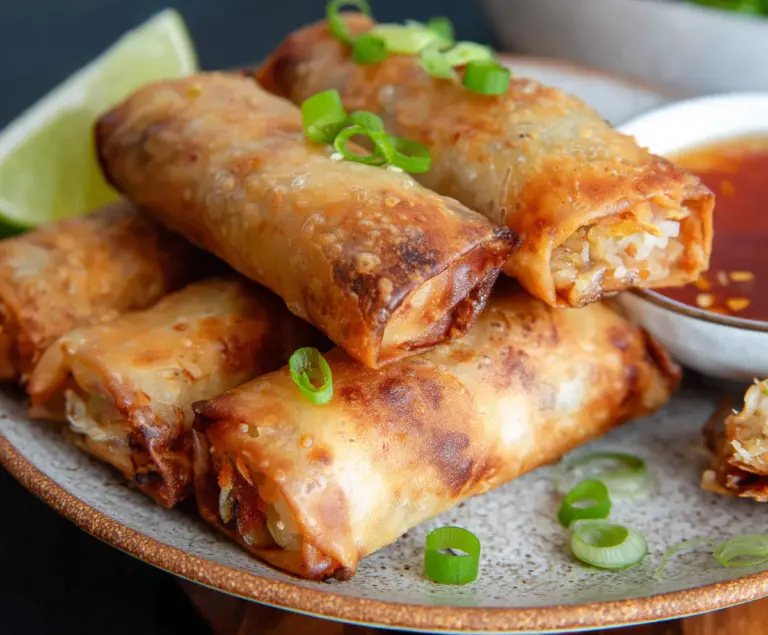 Crispy air fryer spring rolls with fresh vegetables and dipping sauce on a plate