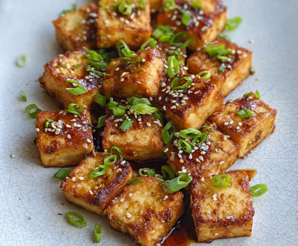 Crispy Air Fryer Tofu served on a plate with fresh vegetables, perfect for a healthy vegan meal.