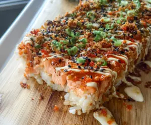 Delicious spicy salmon sushi bake with crispy top and creamy interior, perfect for sushi lovers.
