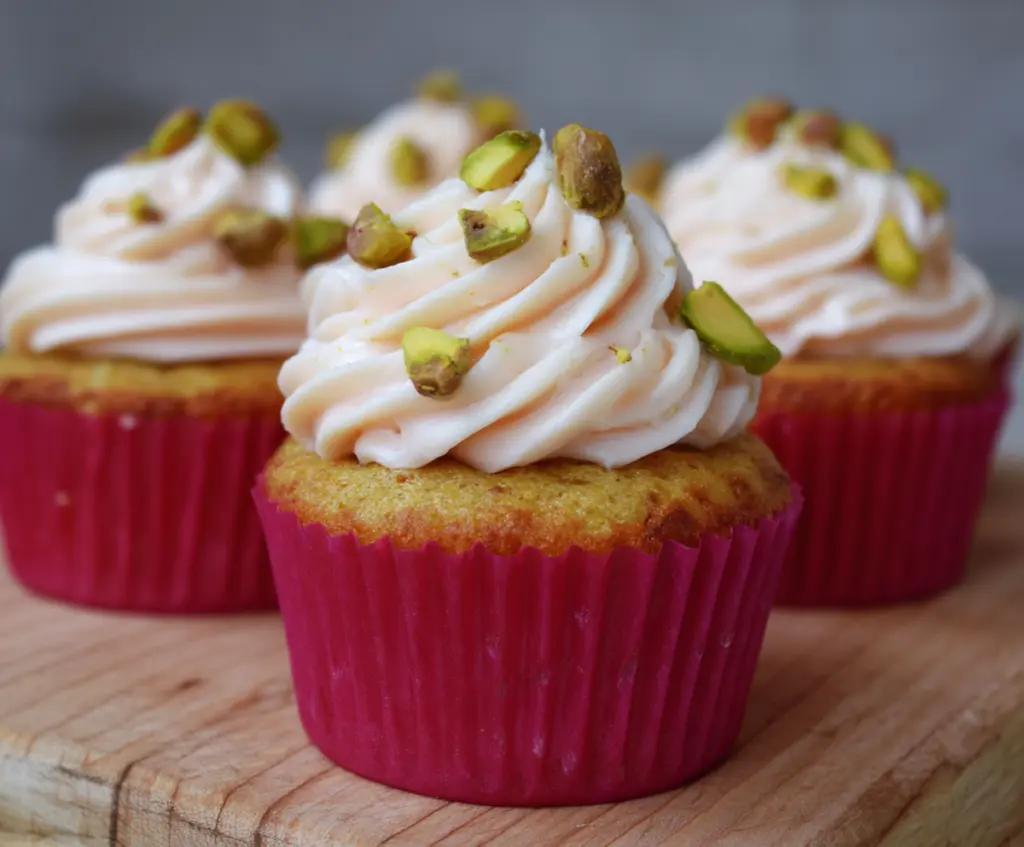 Delicious honey pistachio rosewater cupcakes topped with rose petals and pistachios.