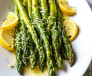 Delicious Lemon Butter Asparagus dish garnished with fresh lemon slices and herbs.